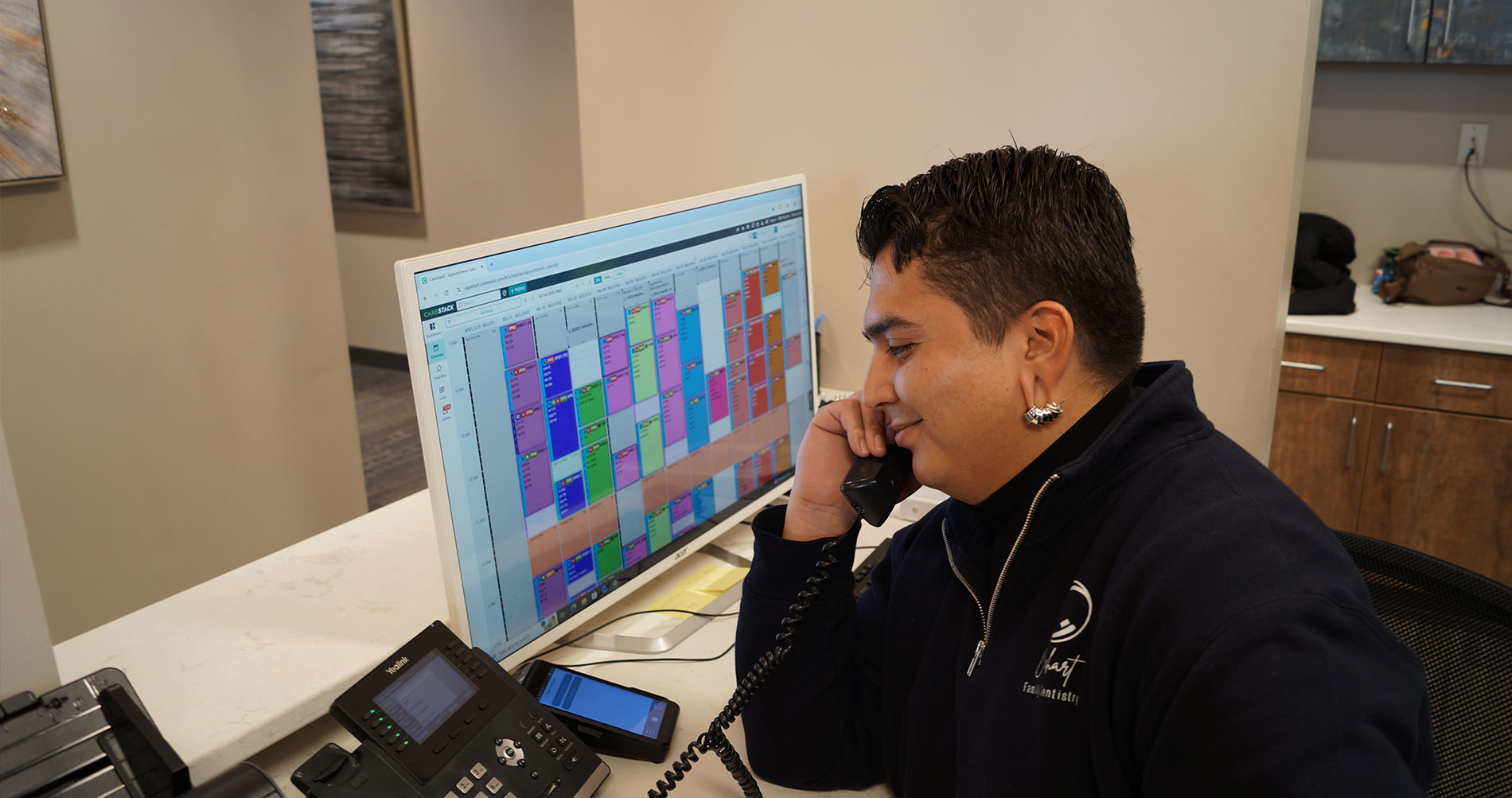 The image shows a man sitting in a dental chair, receiving treatment from a dentist who is standing behind him.